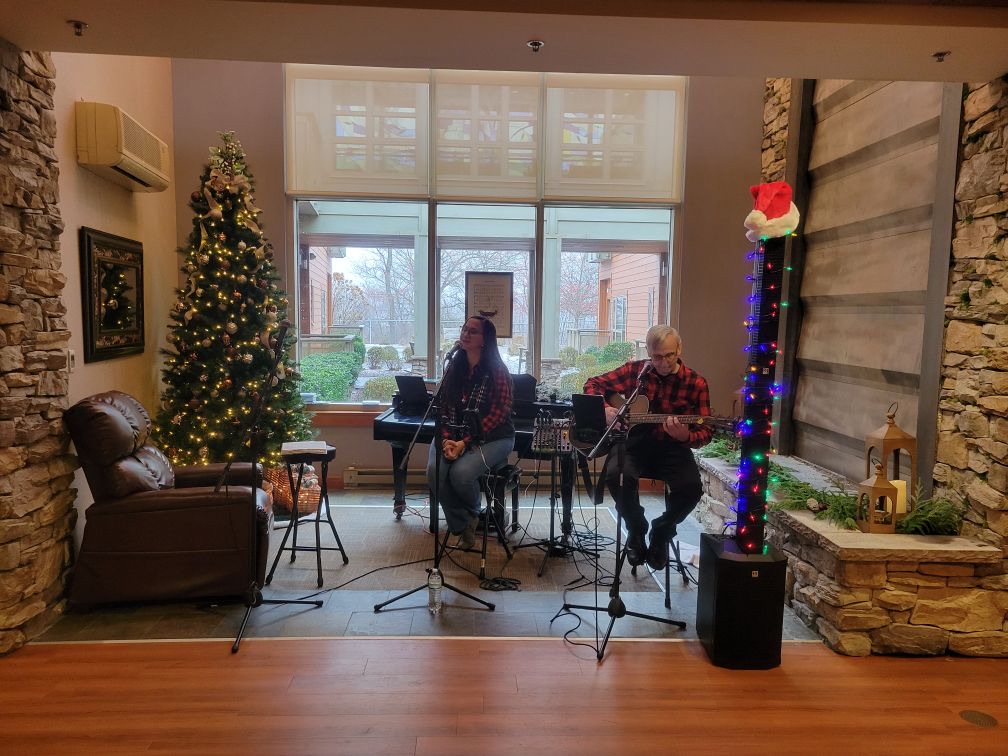 A Christmas worship concert beside a decorated tree and stone fireplace