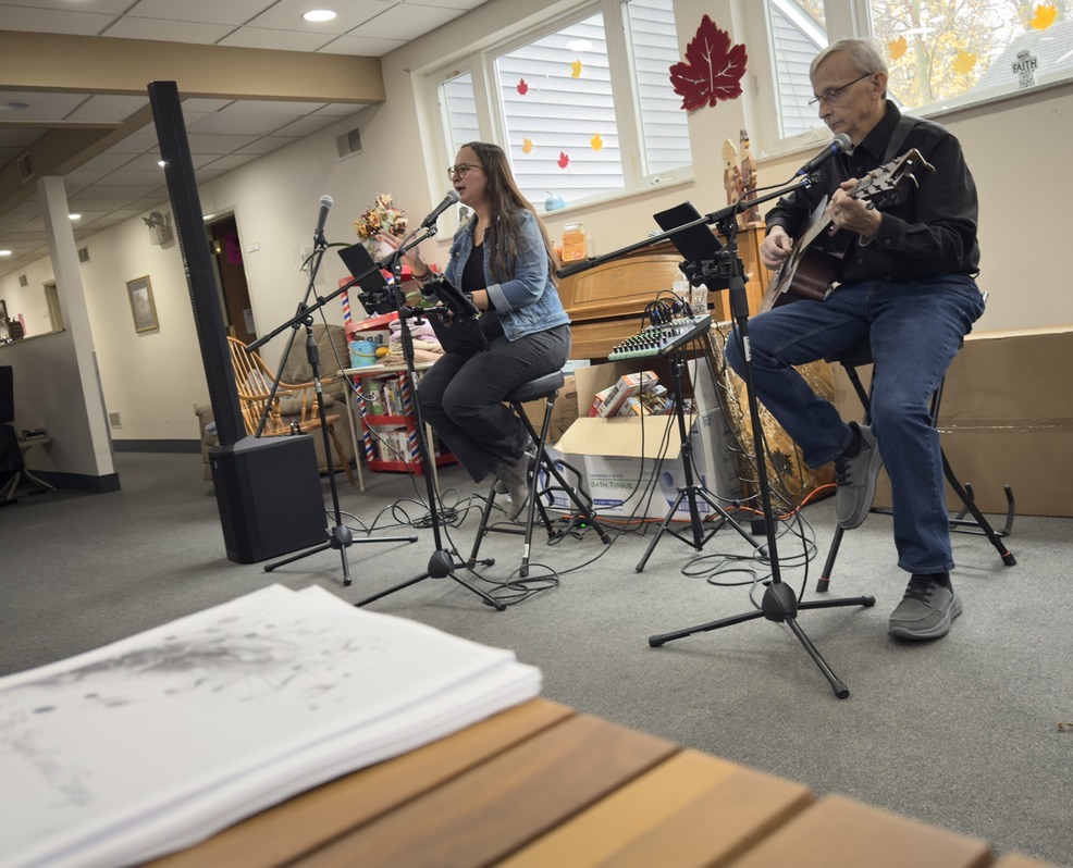 Jess and Keith leading worship with autumn decorations nearby