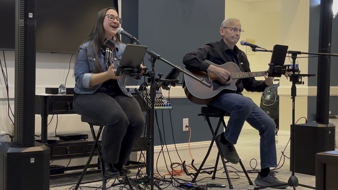 Jess and Keith leading a worship concert with acoustic guitar and vocals