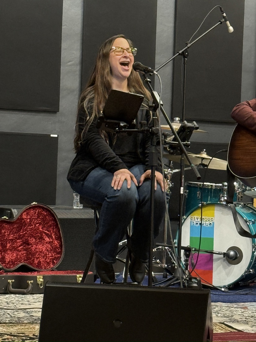 Jess laughing joyfully while singing at the microphone