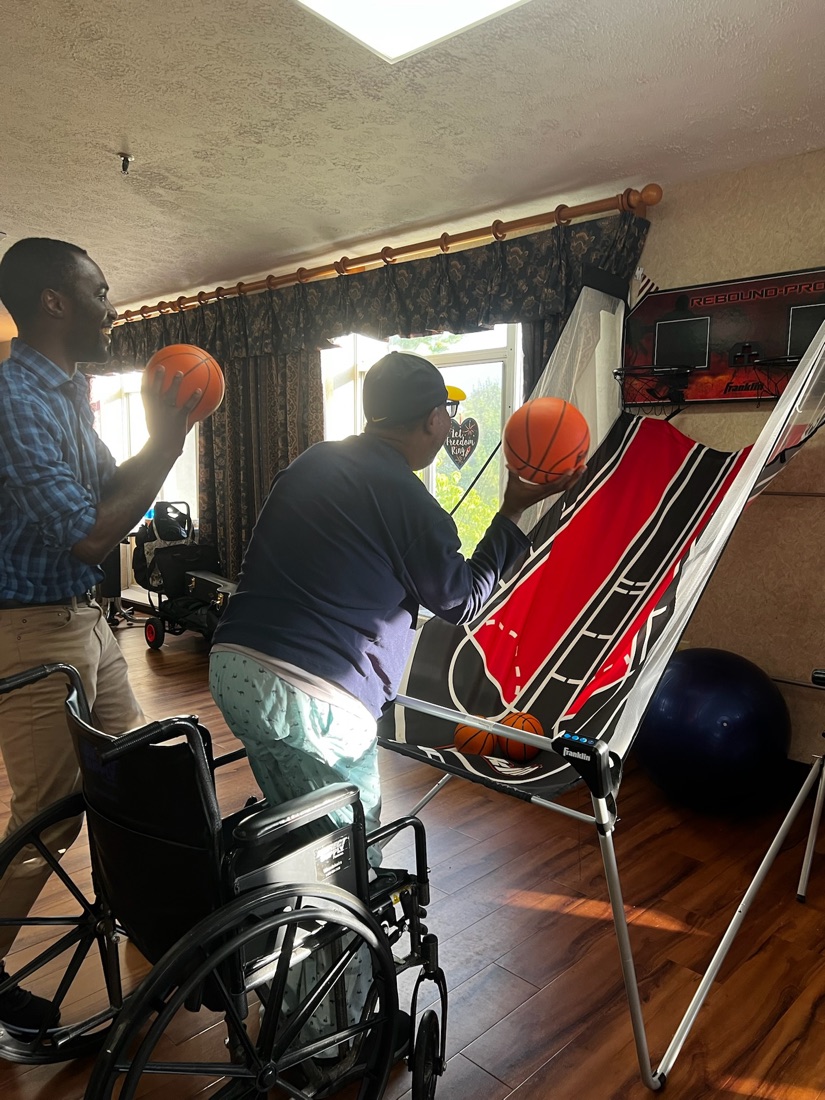 A team member playing an arcade basketball game with a resident